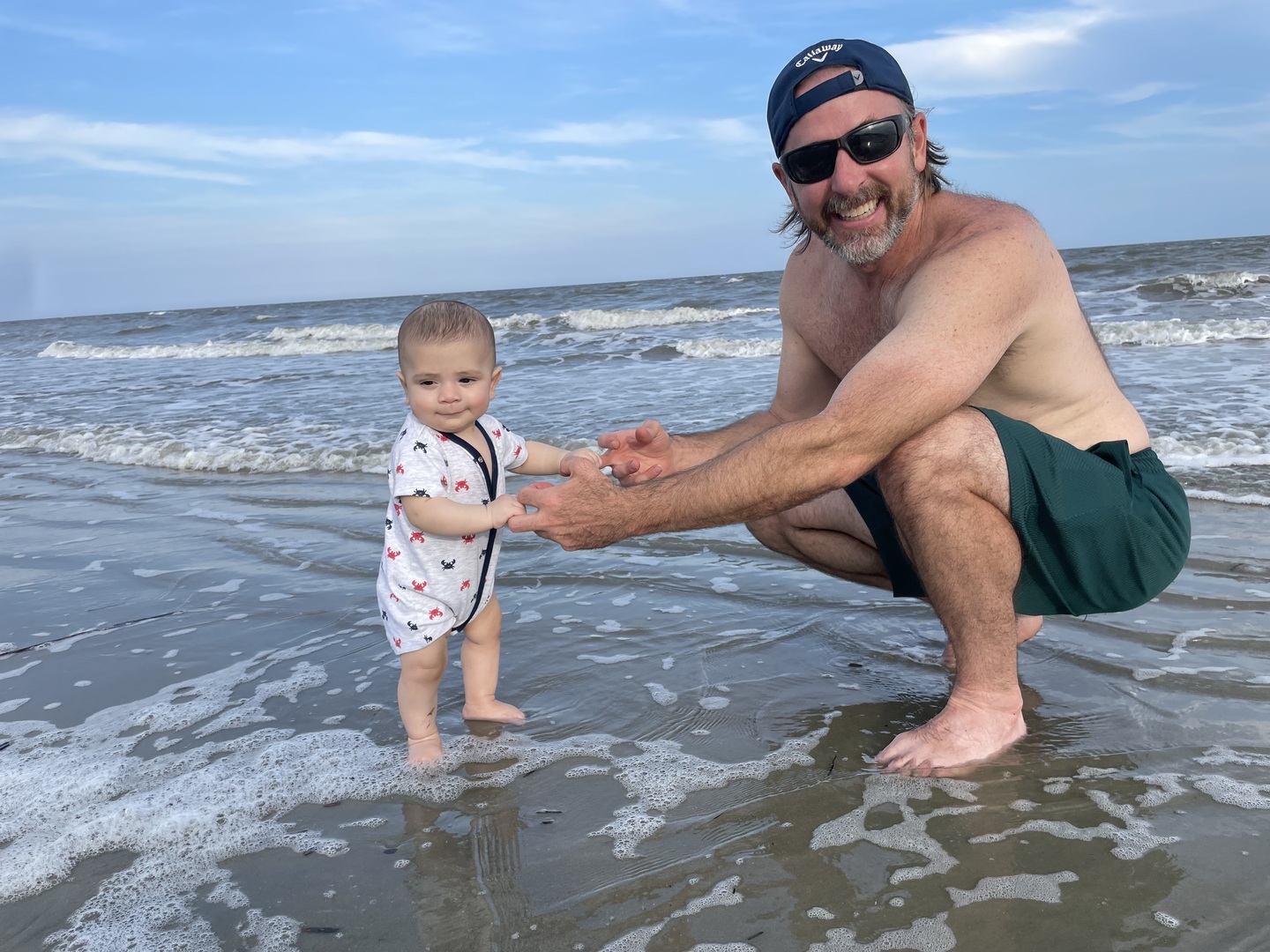 Padrick holding a child’s hands at the ocean